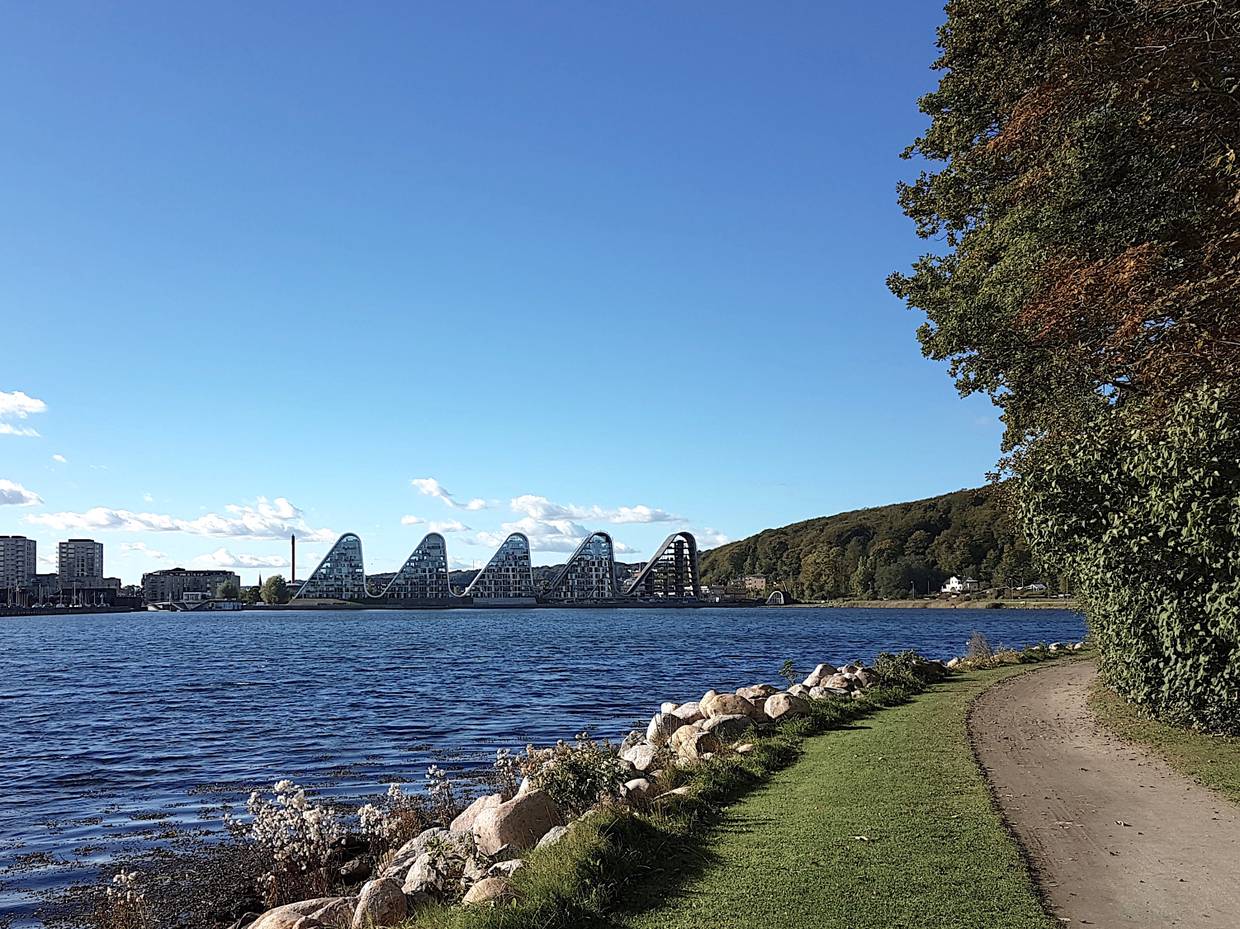 Blick auf vier wellenförmige Häuser am Fjordufer