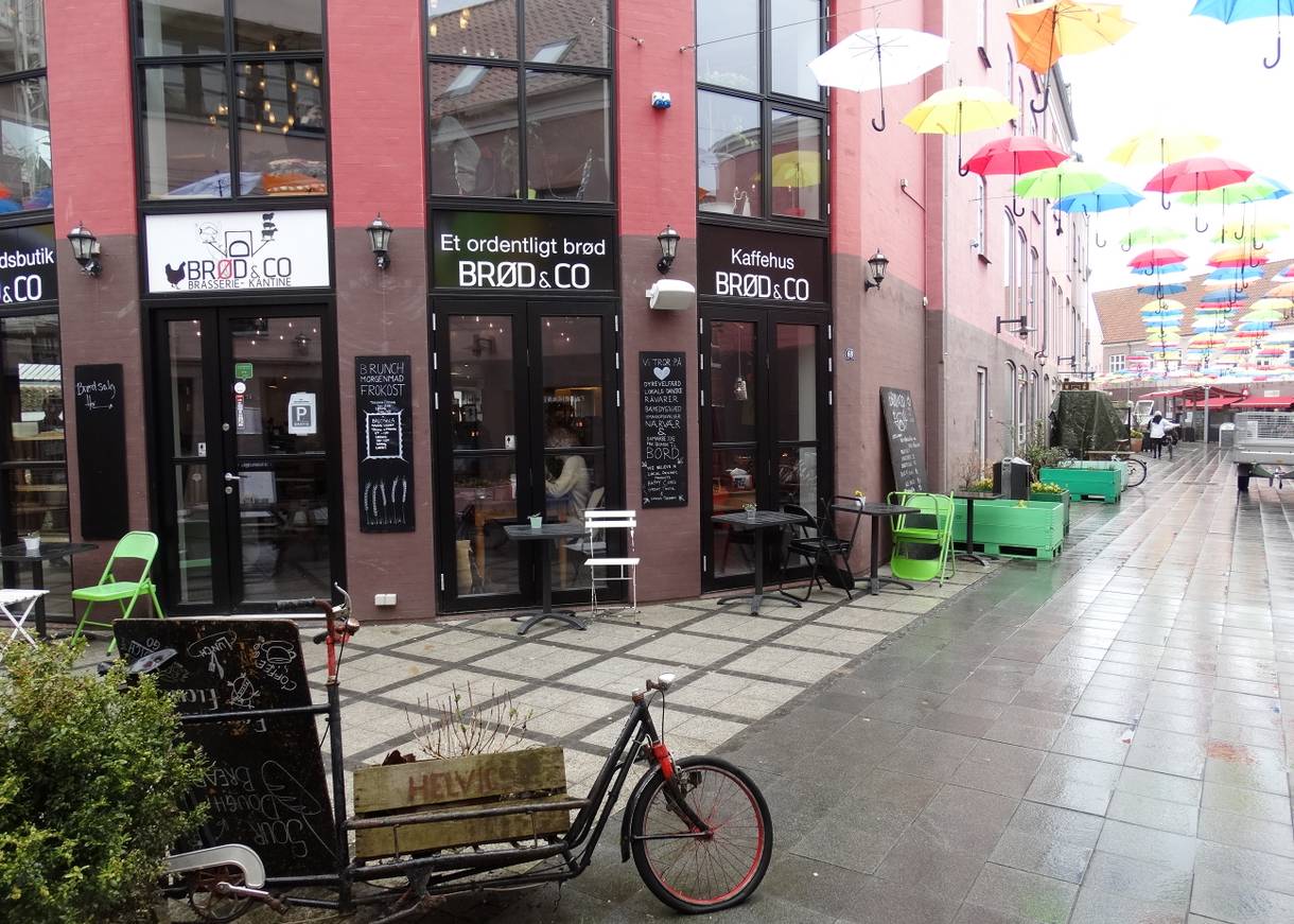 Ecklokal in einem roten Haus, über der Straße bunte Schirme