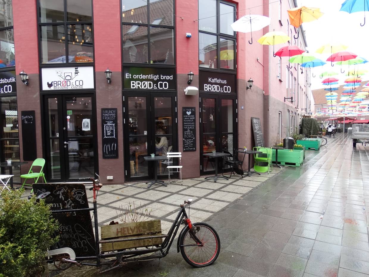 Ecklokal in einem roten Haus, über der Straße bunte Schirme