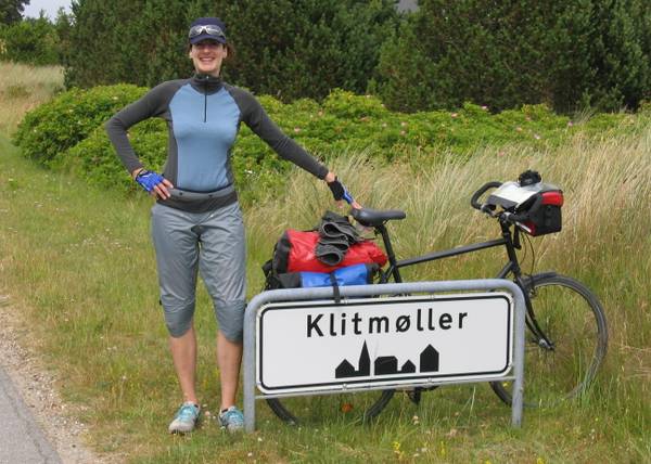 Radlerin mit ihrem Fahrrad neben dem Ortsschild von Klitmøller
