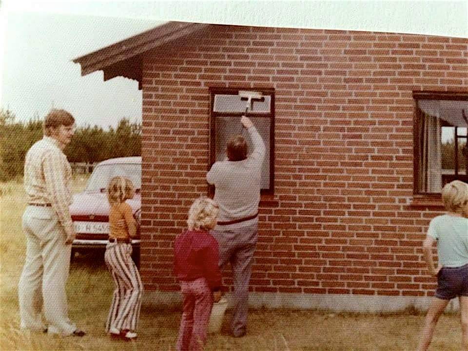 Mann putzt Fenster, Familie schaut zu