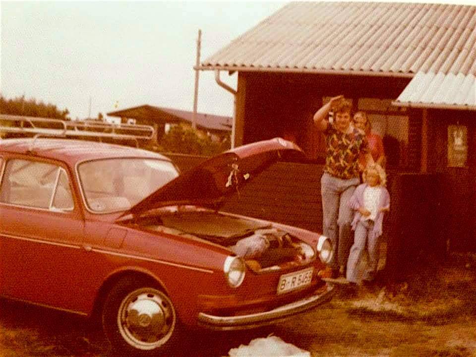 Auto mit offenem Kofferraum vor einem Ferienhaus