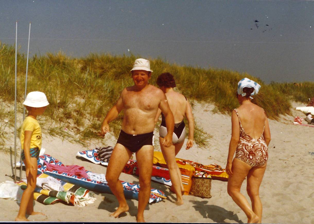 Badegäste mit Luftmatratzen und Sonnenschirm am Strand