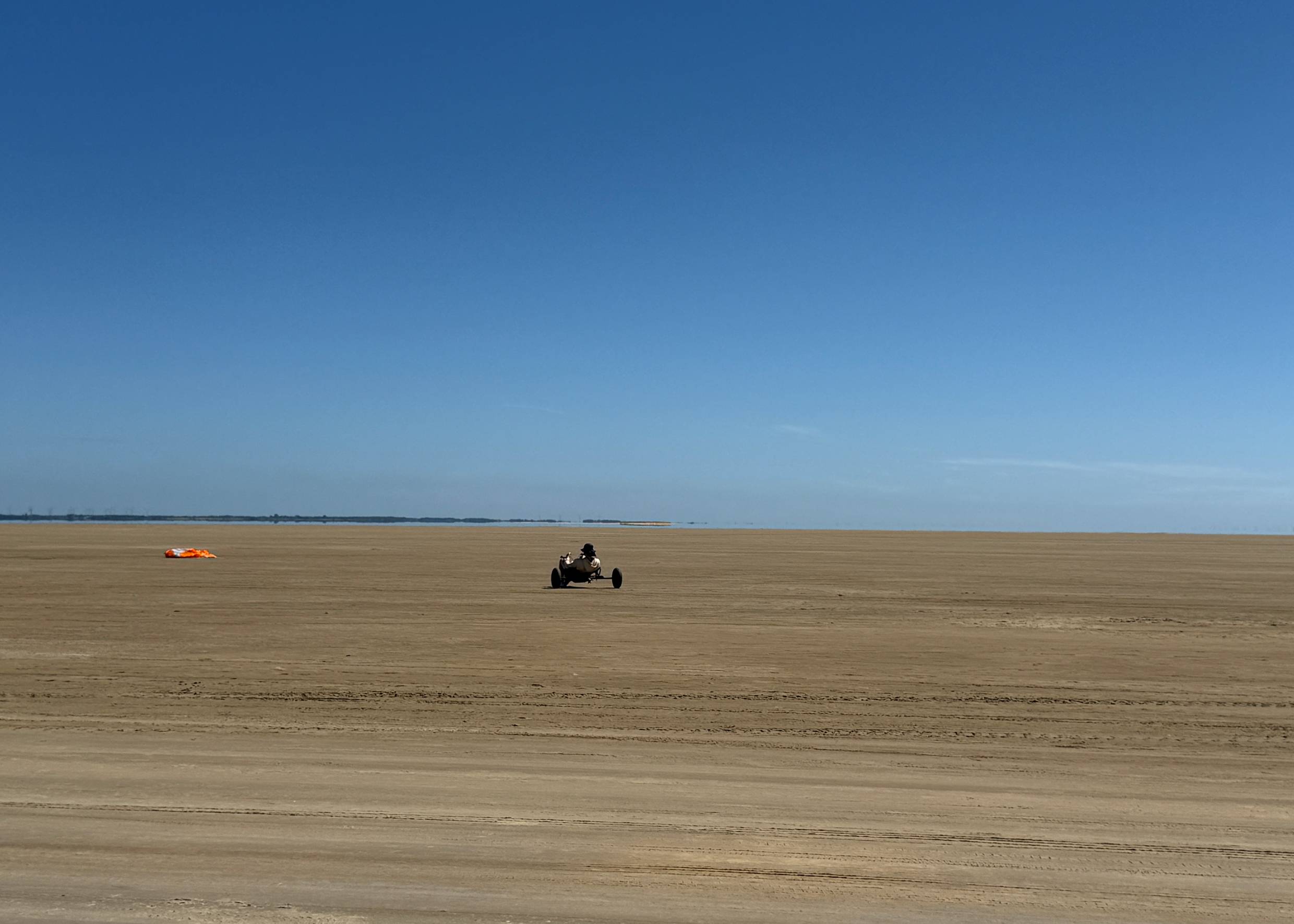 Ein großer Strand mit einem Kitebuggy-Fahrer