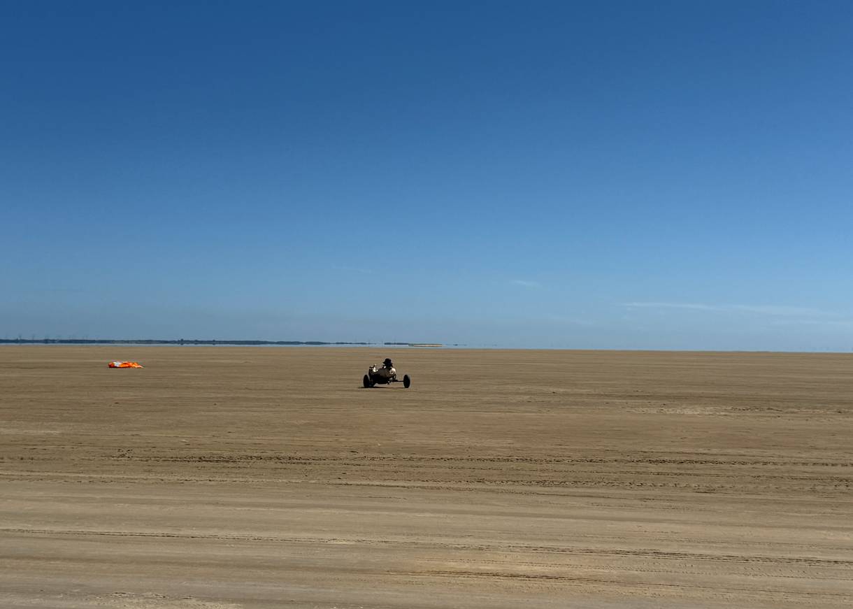 Ein großer Strand mit einem Kitebuggy-Fahrer