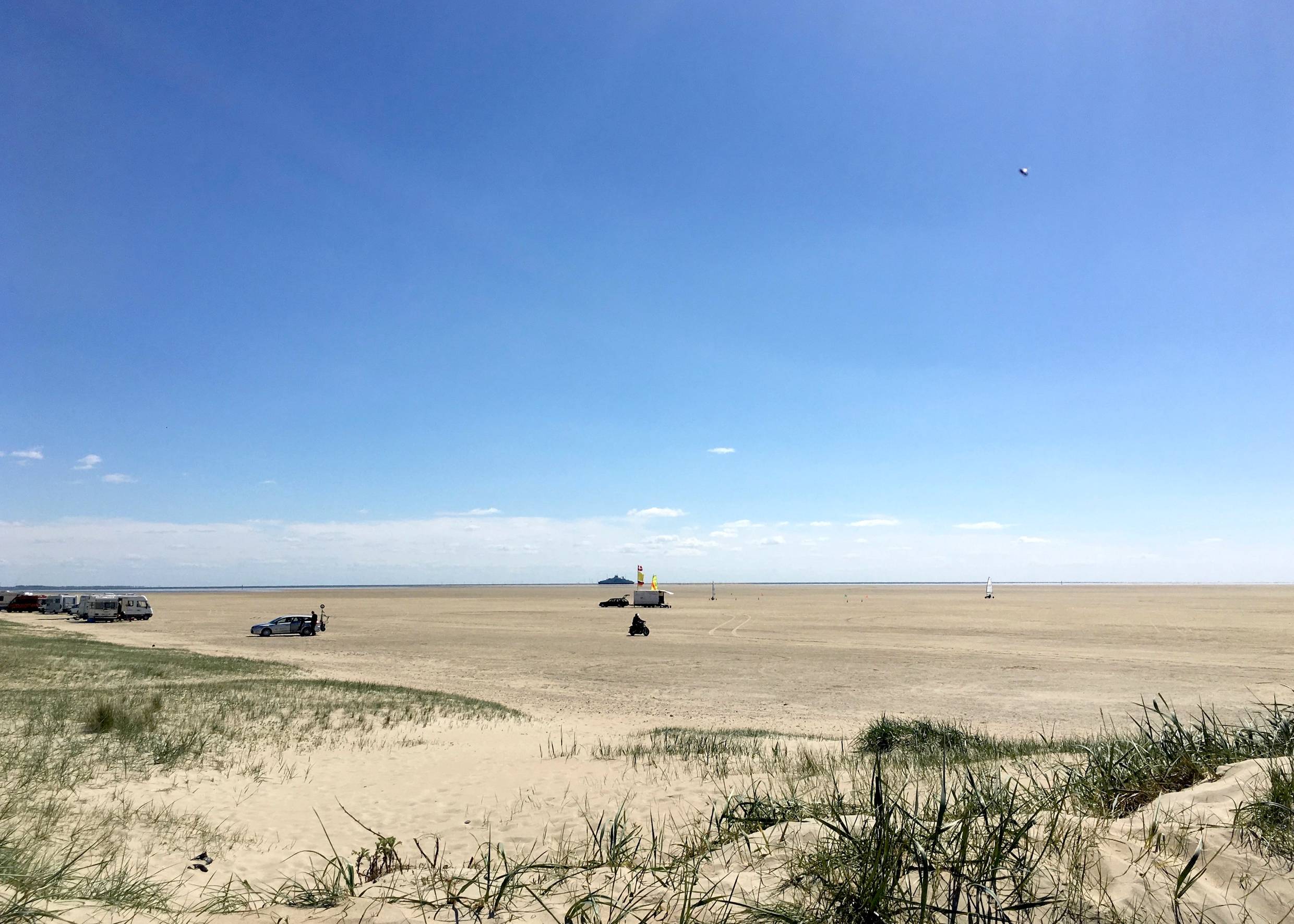 Der sehr breite Sønderstrand, am Horizont ein kleines Schiff im Meer