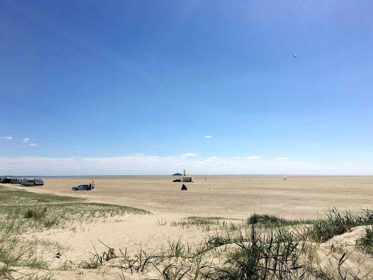 Der sehr breite Sønderstrand, am Horizont ein kleines Schiff im Meer