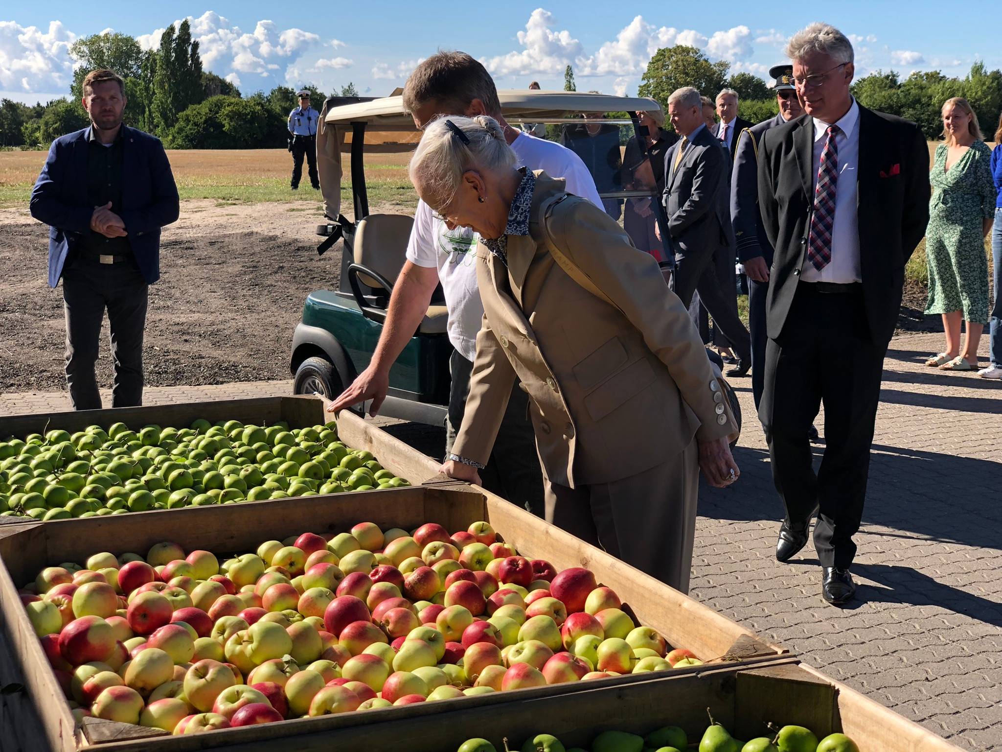 Königin Margrethe schaut auf Kisten mit Äpfel und Birnen