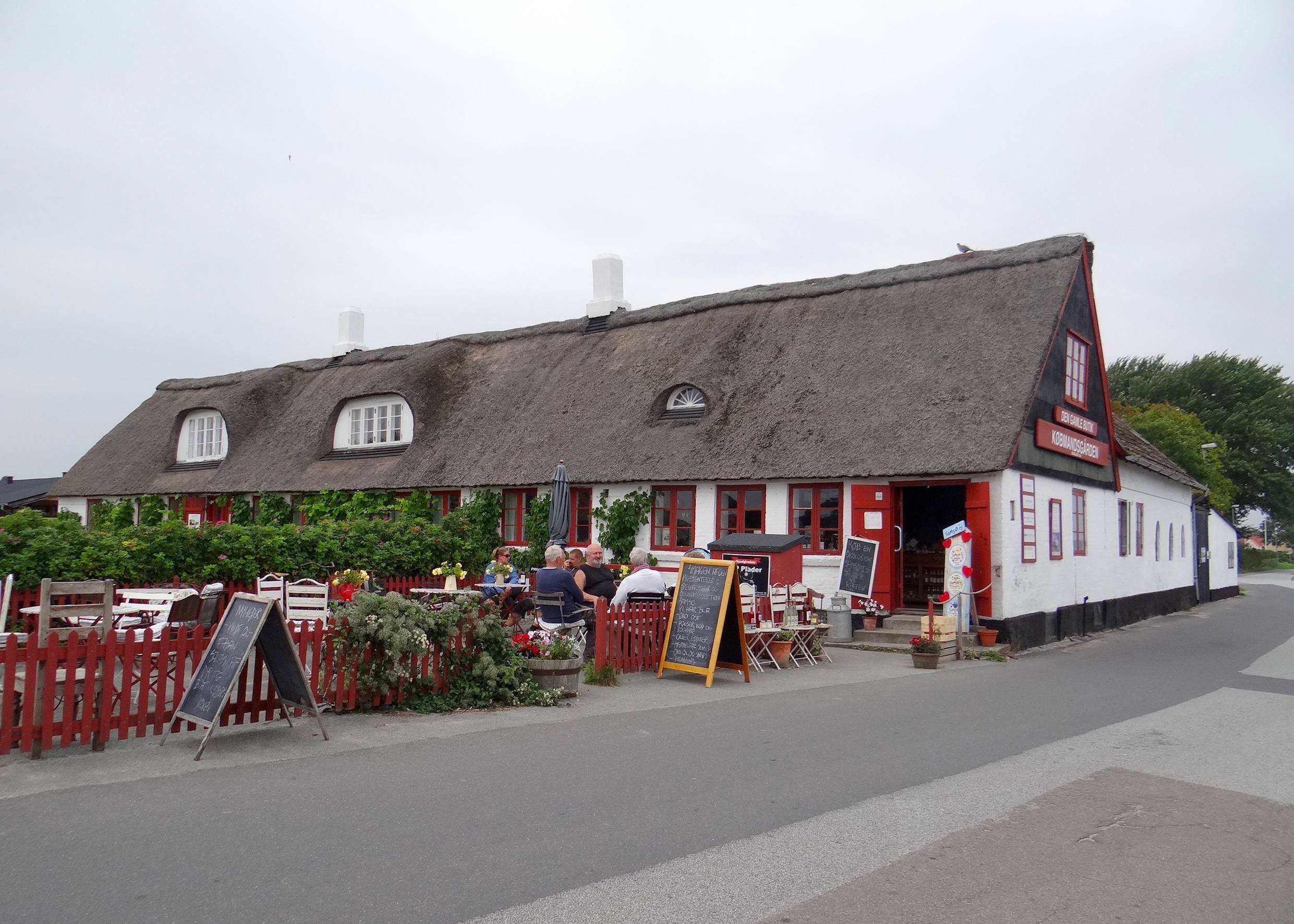 Kleines, rot-weißes Reetdachaus mit Caféterrasse 