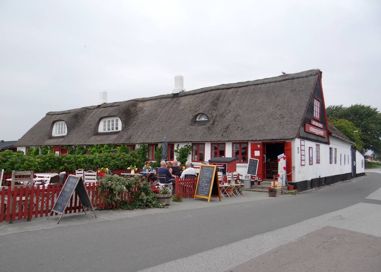 Kleines, rot-weißes Reetdachaus mit Caféterrasse 
