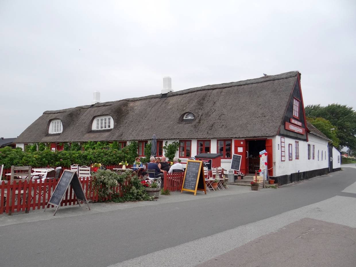 Kleines, rot-weißes Reetdachaus mit Caféterrasse 