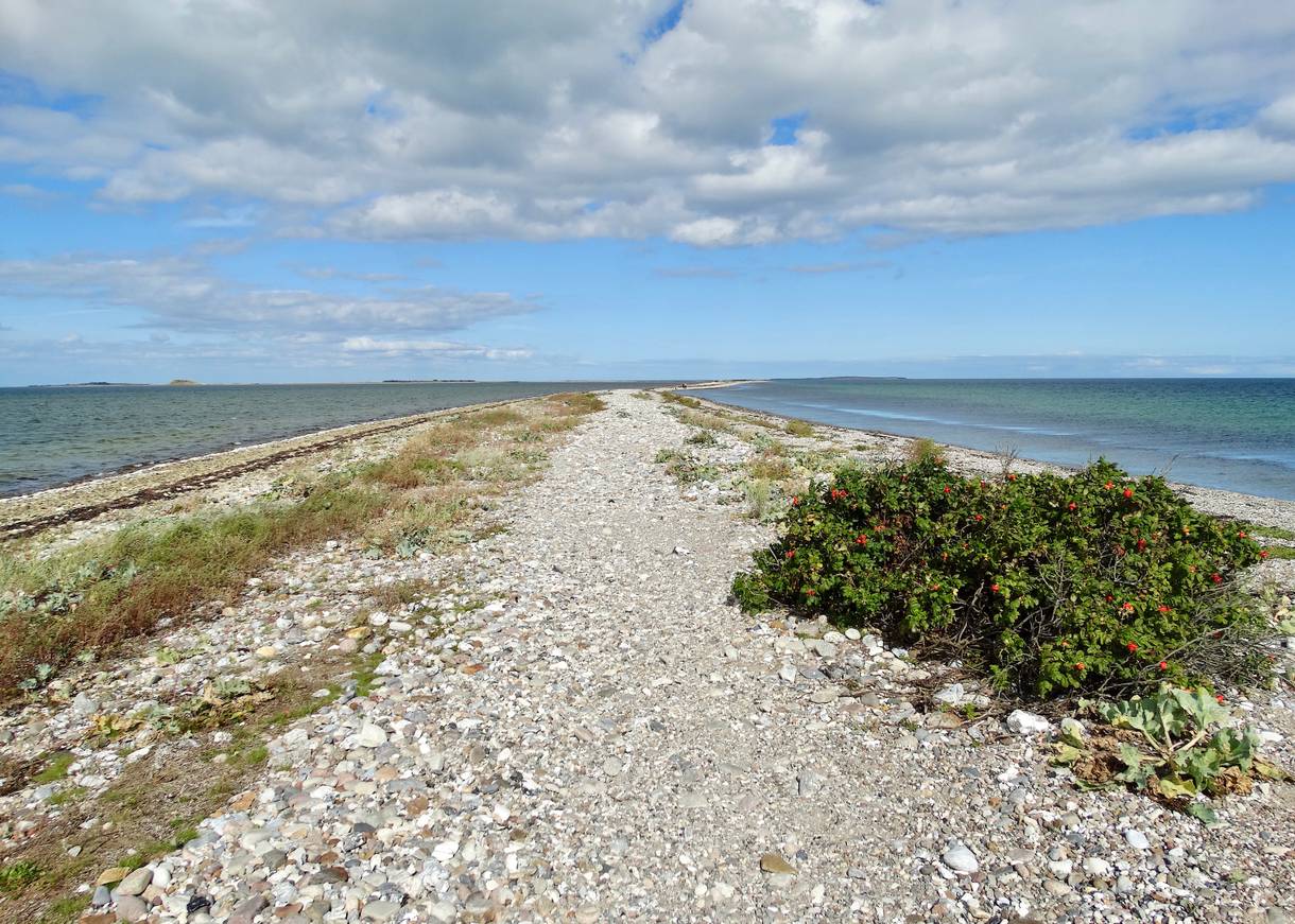 Schmaler Steinstrand, auf beiden Seiten von Wasser umgeben