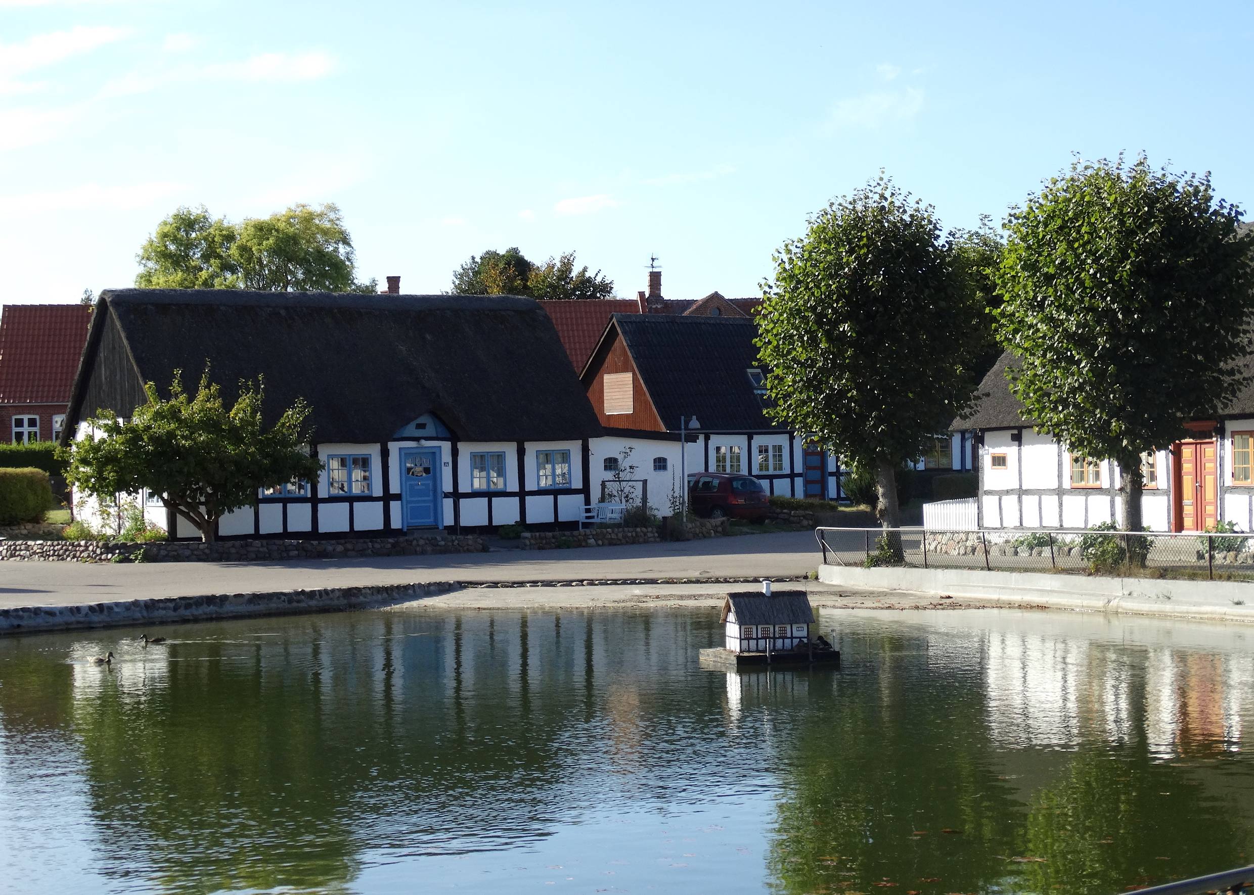 Dorfteich zwischen weißen Reetdachhäusern