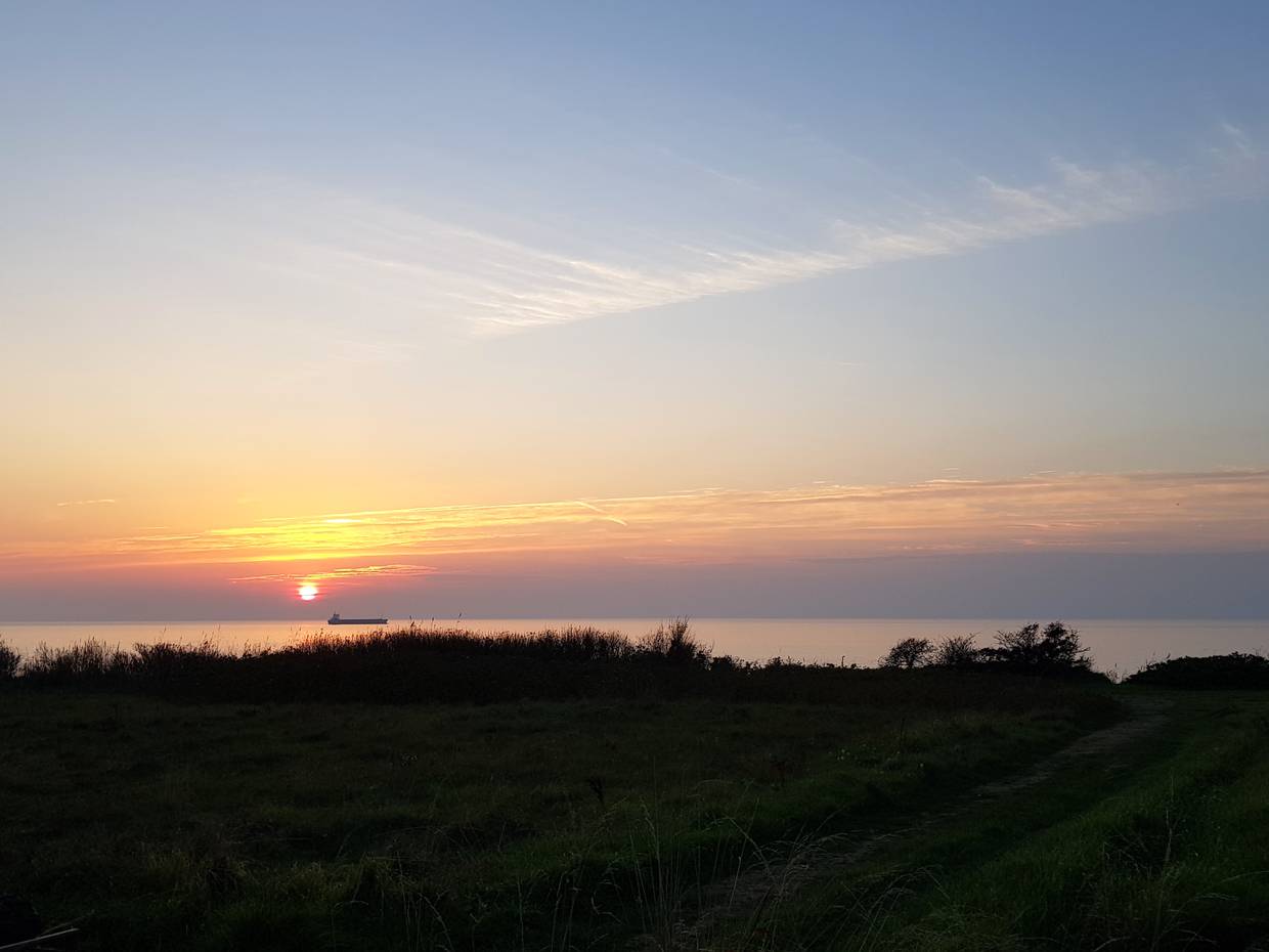 Sonnenuntergang über dem Meer, ein Tanker am Horizont