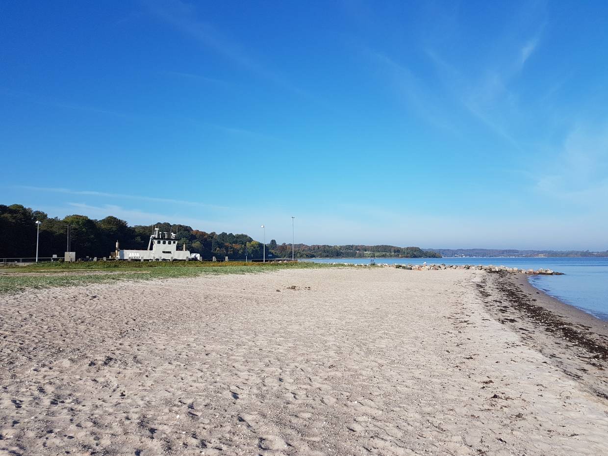 Sandstrand, im Hintergrund eine kleine Fähre