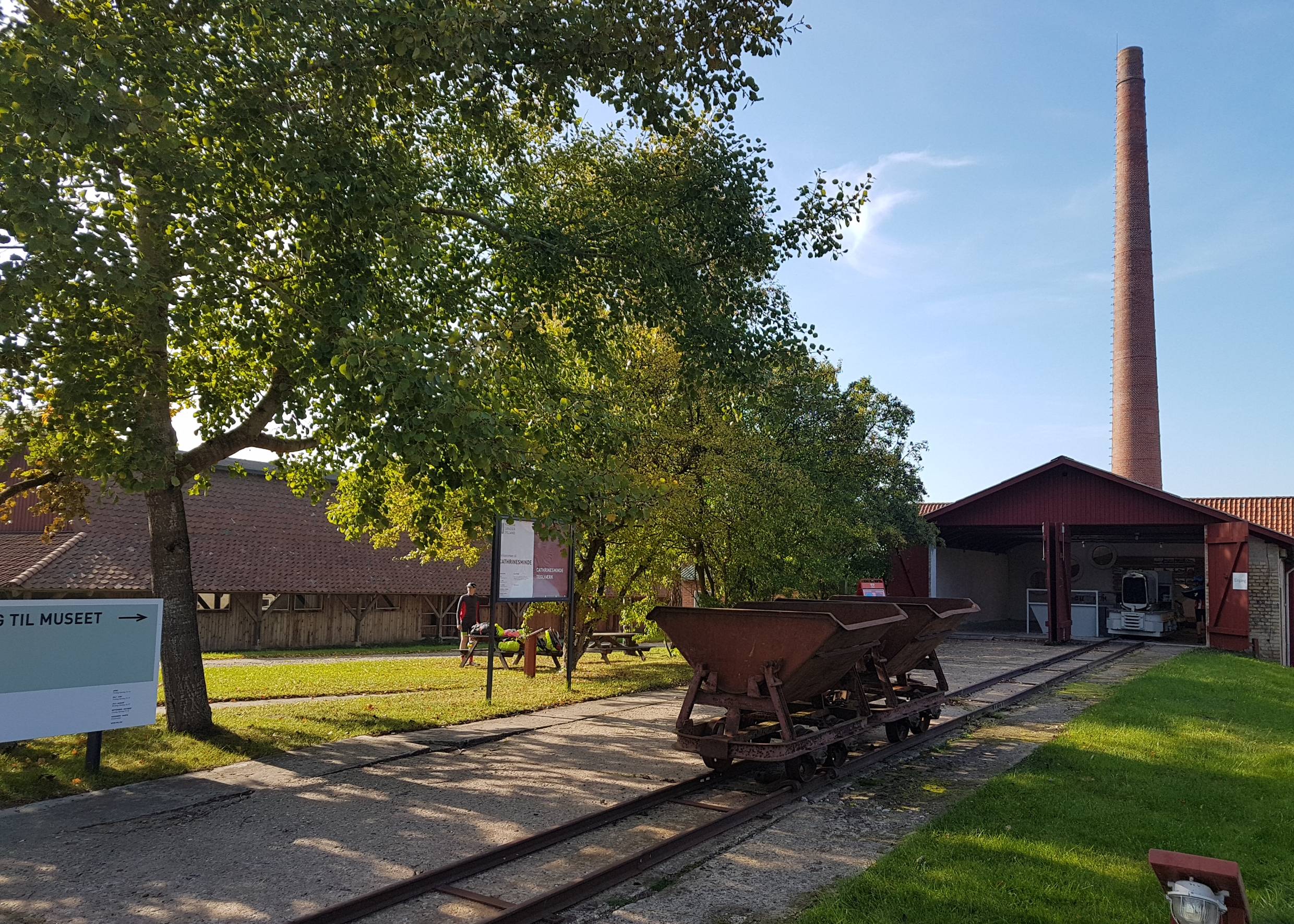 Der Eingang des Ziegeleimuseums mit einer alten Lore und dem Schornstein im Hintergrund