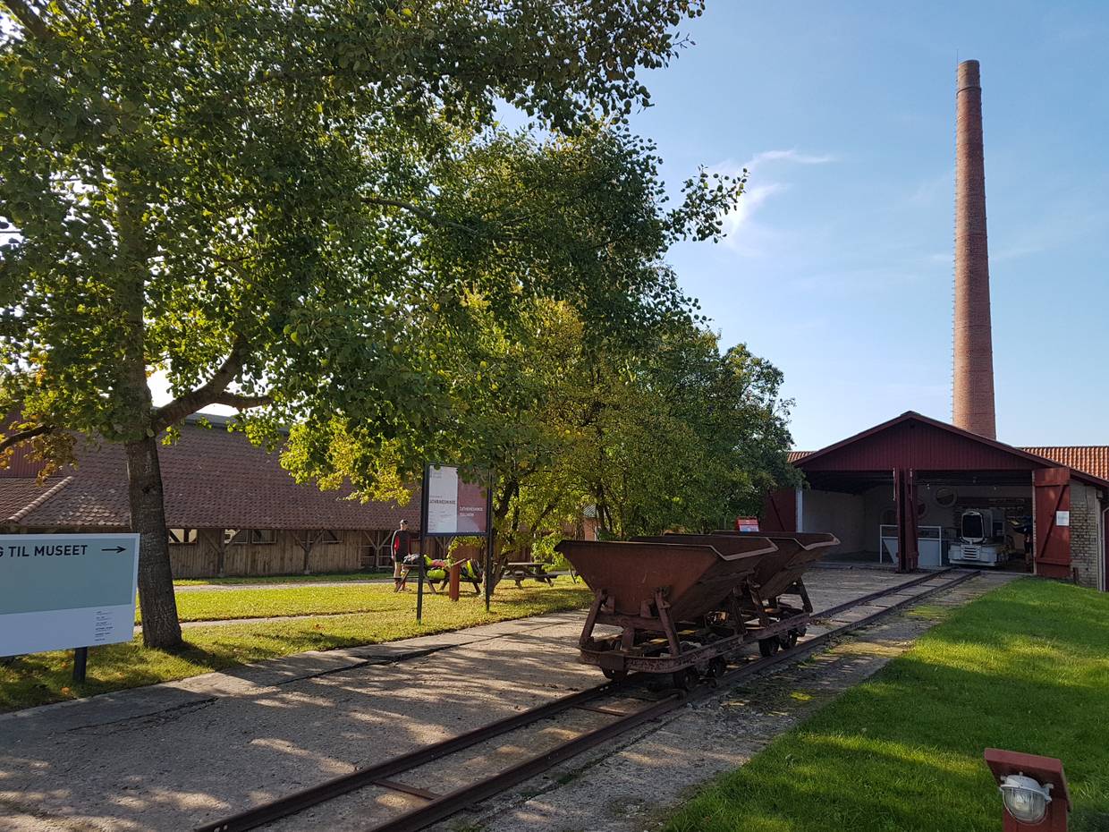 Der Eingang des Ziegeleimuseums mit einer alten Lore und dem Schornstein im Hintergrund