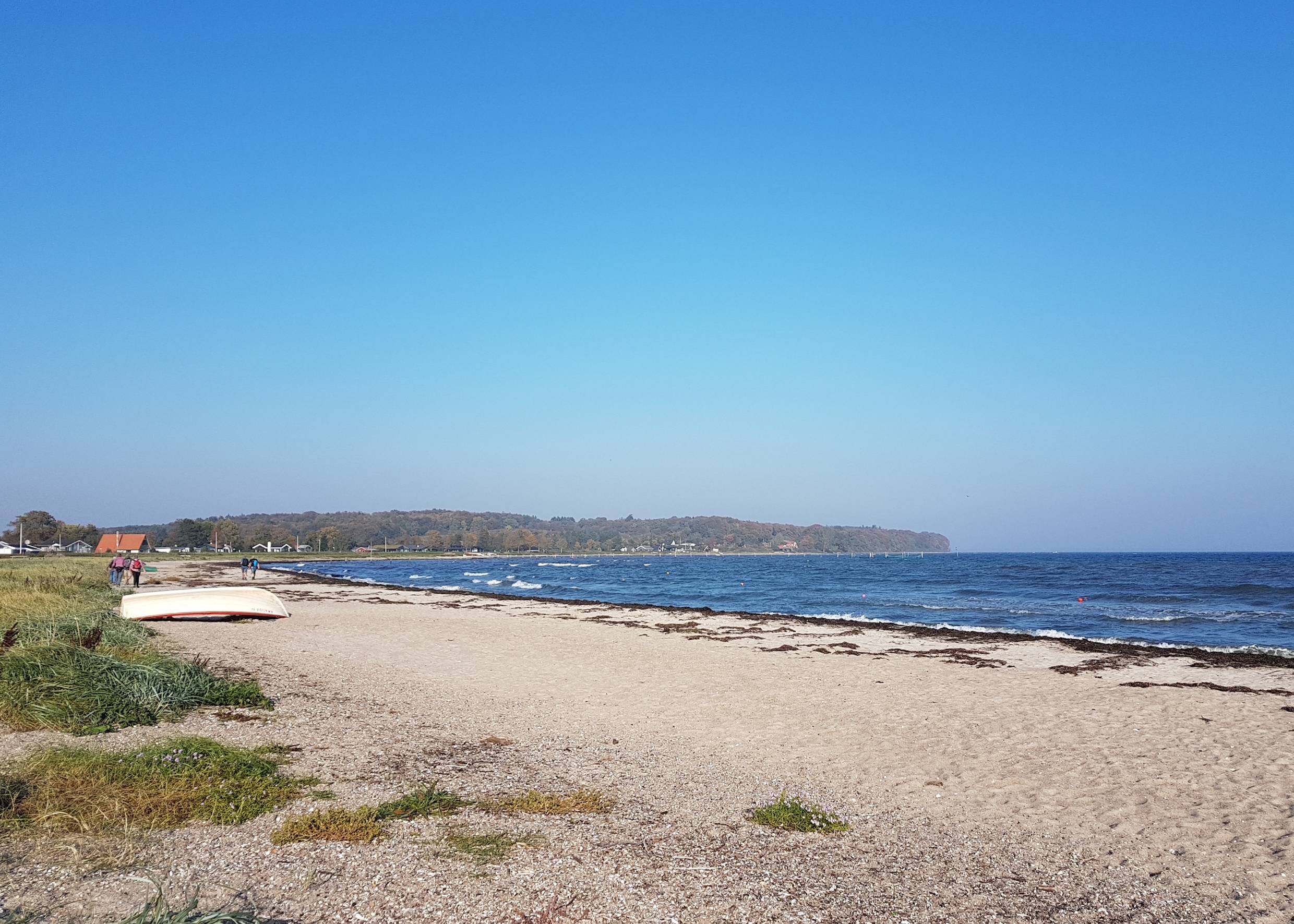 Blick auf die flache Diernaes Bucht mit breitem Strand und Ferienhäusern
