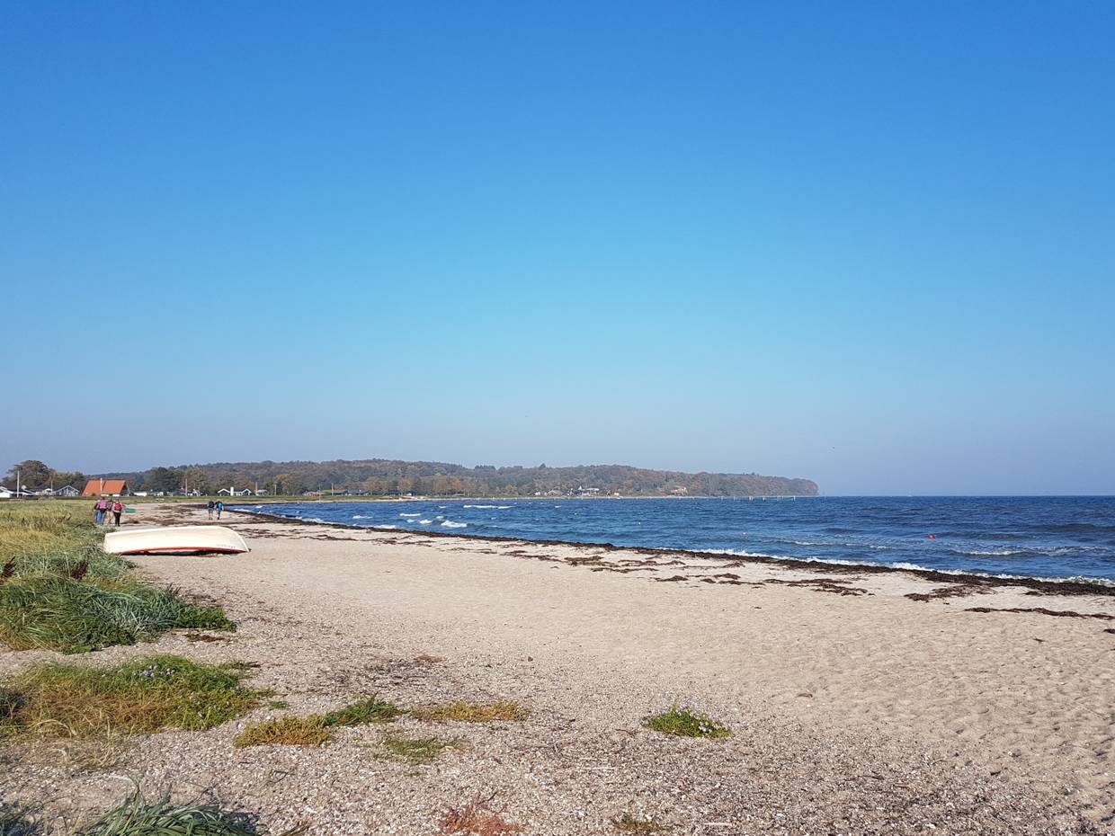 Blick auf die flache Diernaes Bucht mit breitem Strand und Ferienhäusern