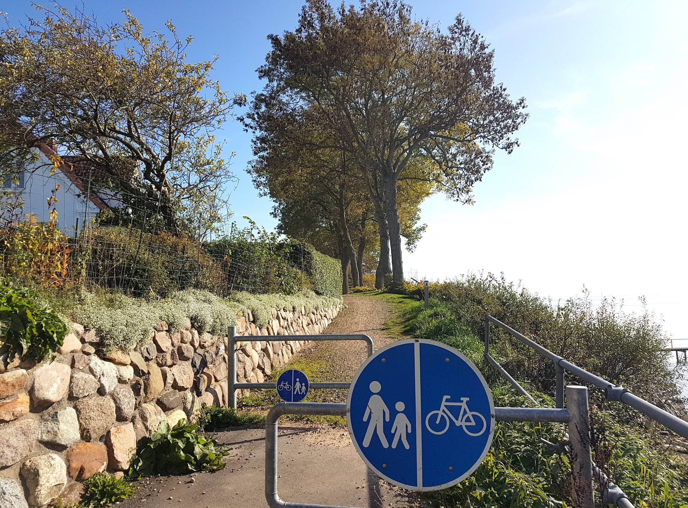 Eingang zu einem Fußweg am Ufer mit einer Sperre für Radfahrer