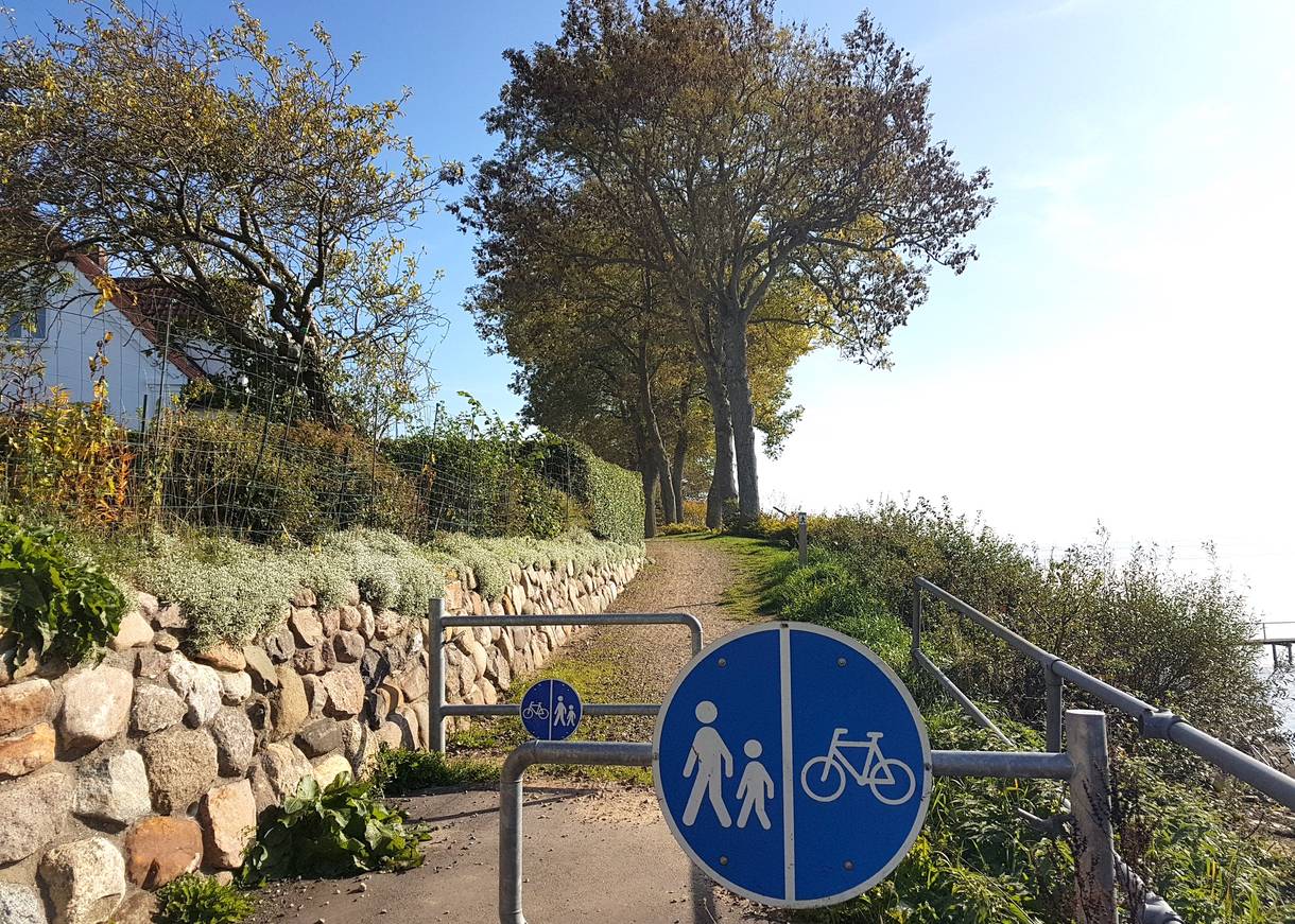 Eingang zu einem Fußweg am Ufer mit einer Sperre für Radfahrer