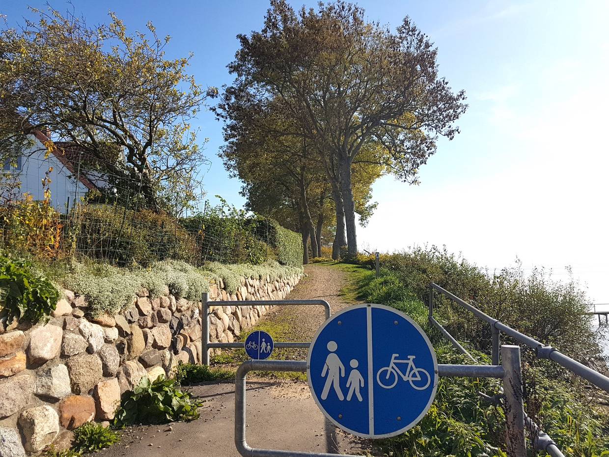 Eingang zu einem Fußweg am Ufer mit einer Sperre für Radfahrer