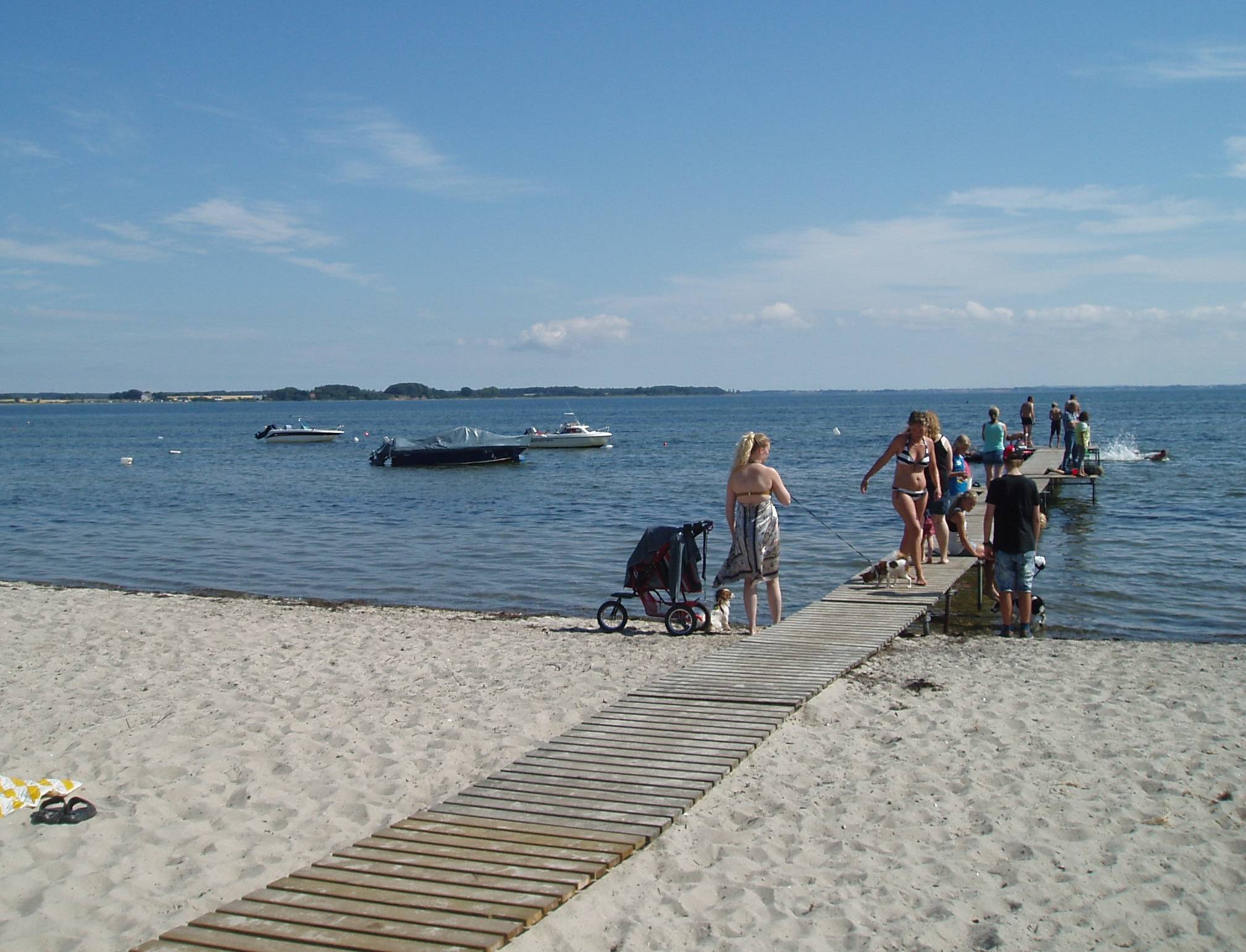 Holzsteg mit vielen Badegästen, Kinderwagen und Hunden an der Ostsee