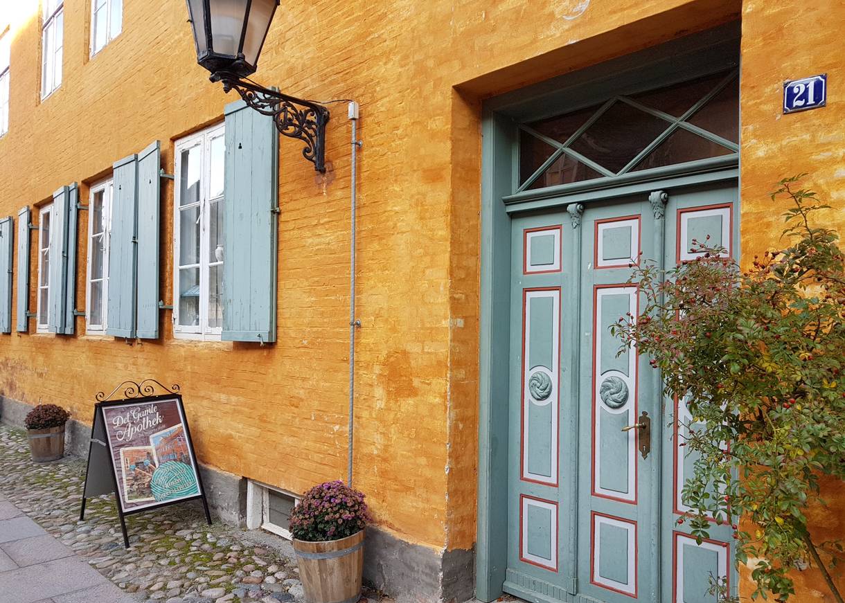 Gelbes Stadthaus mit hellgrünen Türen