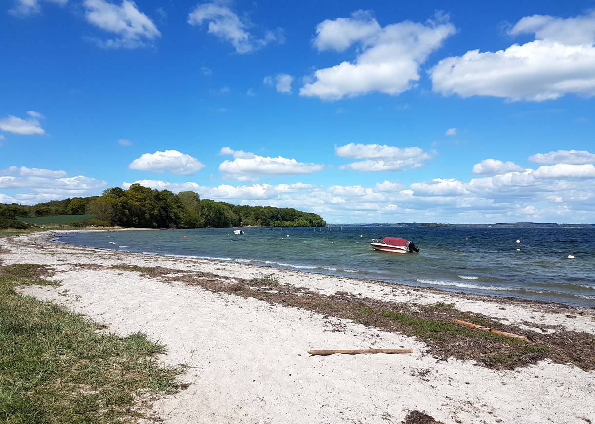 Motorboot an einer Boje vor einem schmalen Sandstrand