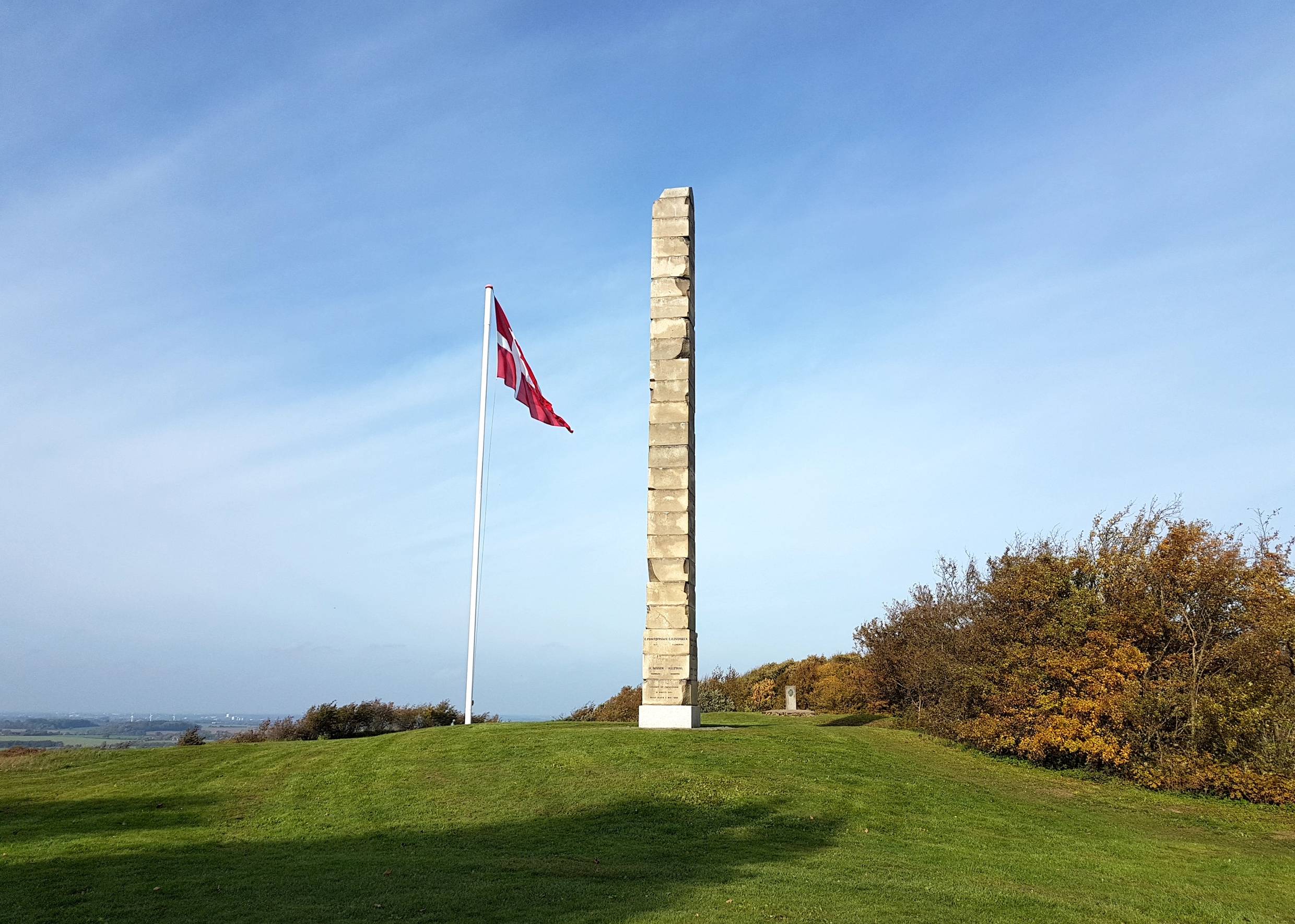 Denkmal aus vielen schmalen Granitsteinen mit einem Dannebrog daneben
