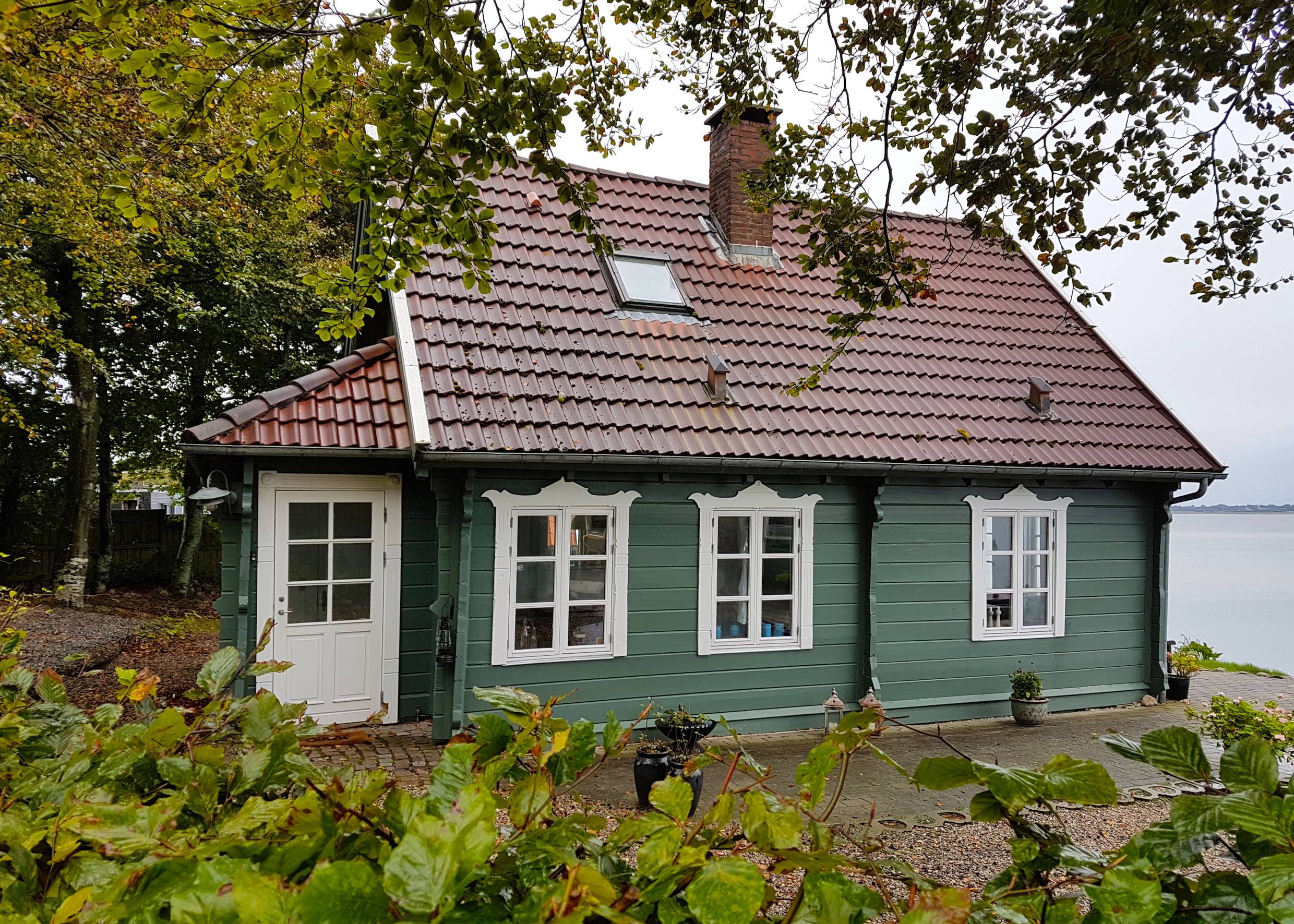 Schmuckes, grünes Holzhaus oberhalb einer Steilküste