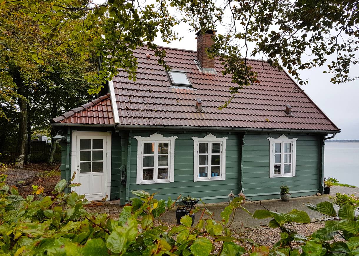 Schmuckes, grünes Holzhaus oberhalb einer Steilküste