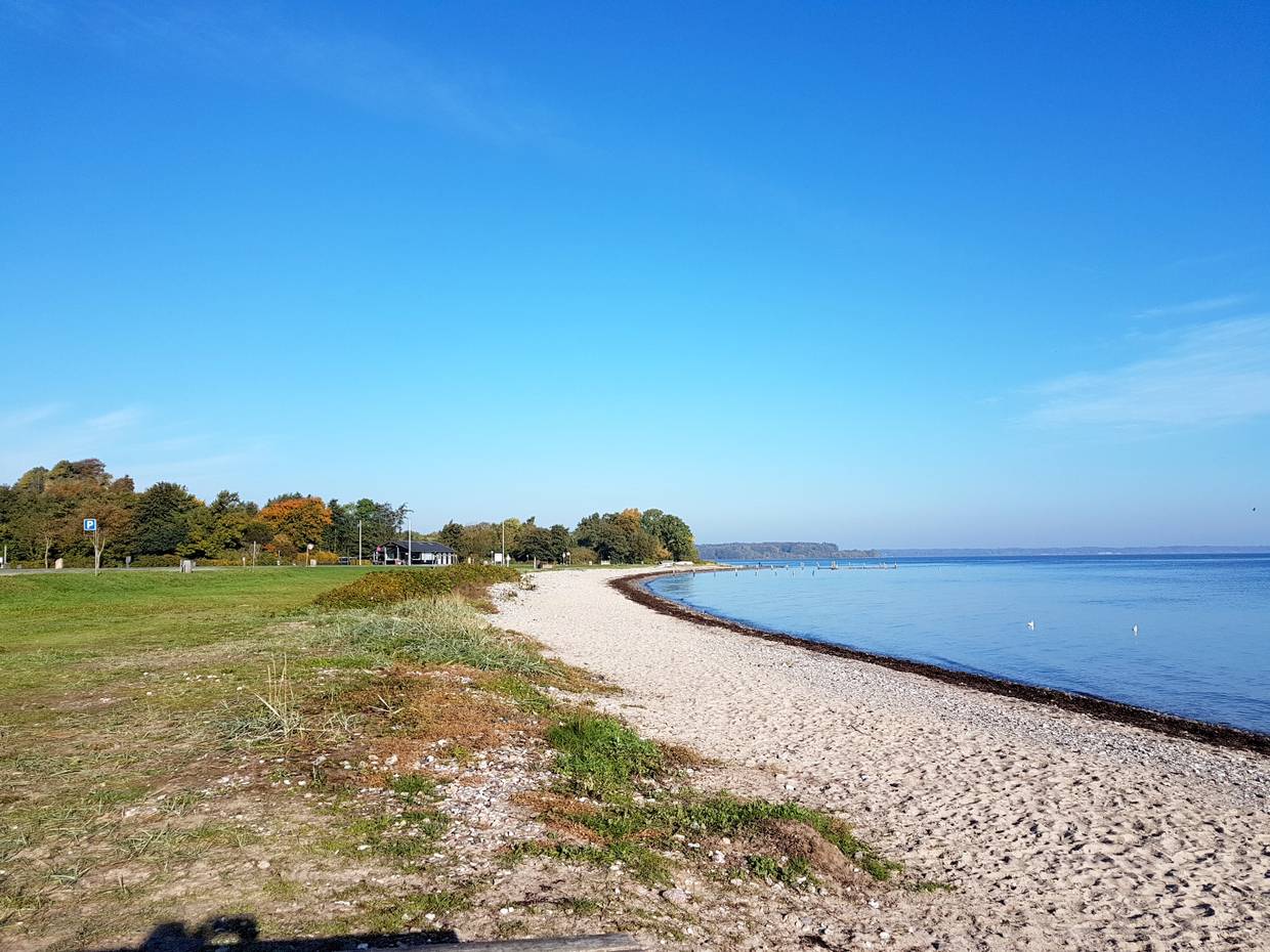 Schmaler Strand mit einer Wiese, sehr stilles blaues Meer 