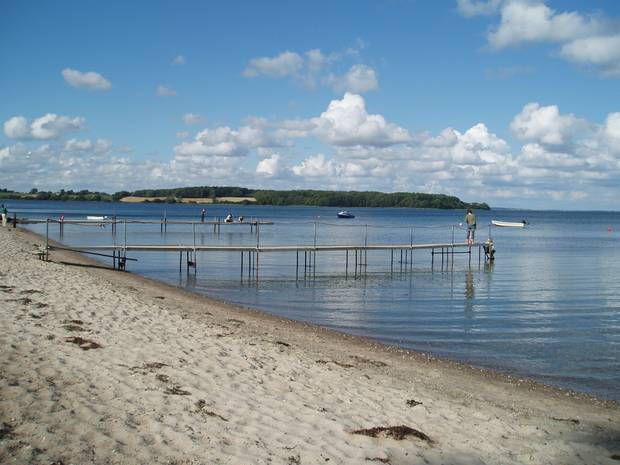 Aussicht über ein stilles Meer, zwei Badesteege ragen ins Wasser