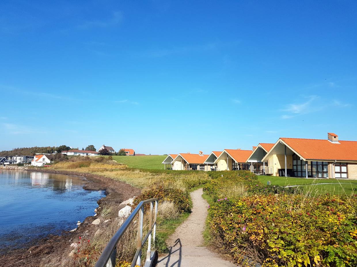 verschiedene Ferienhäuser an der Küste, davor ein Wanderweg