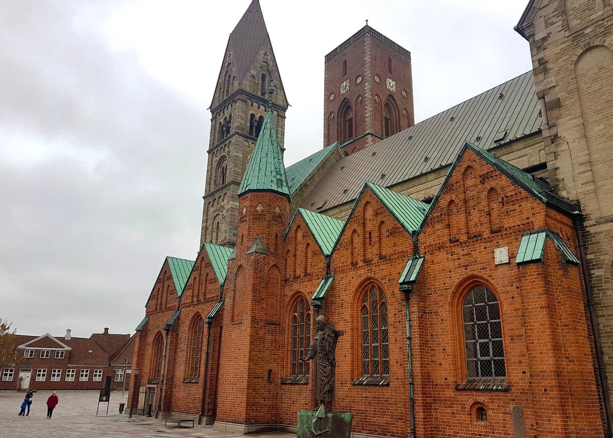 Seitenfront des Doms in Ribe, davor eine Bronzeplastik
