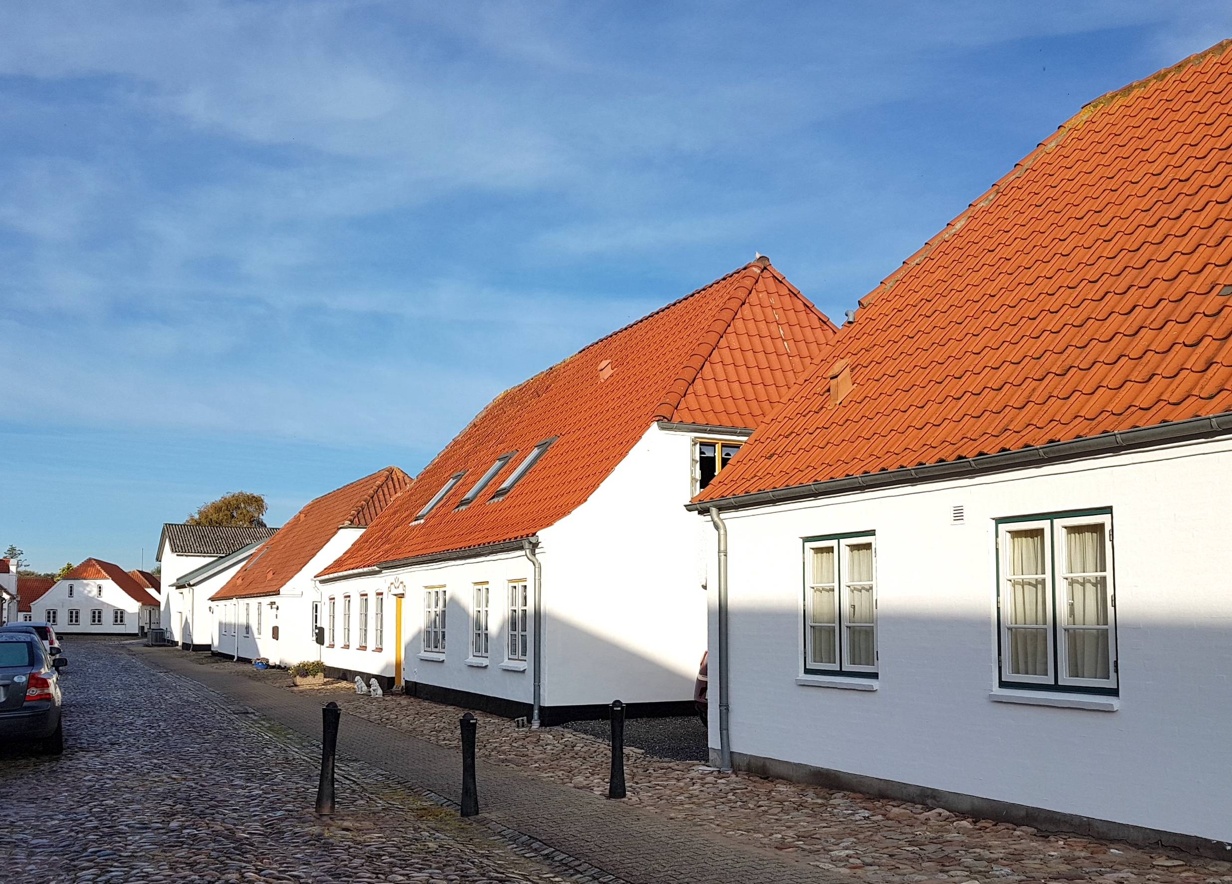 Weiße, recht schmucklose Häuser an einer Kopfsteinpflastergasse