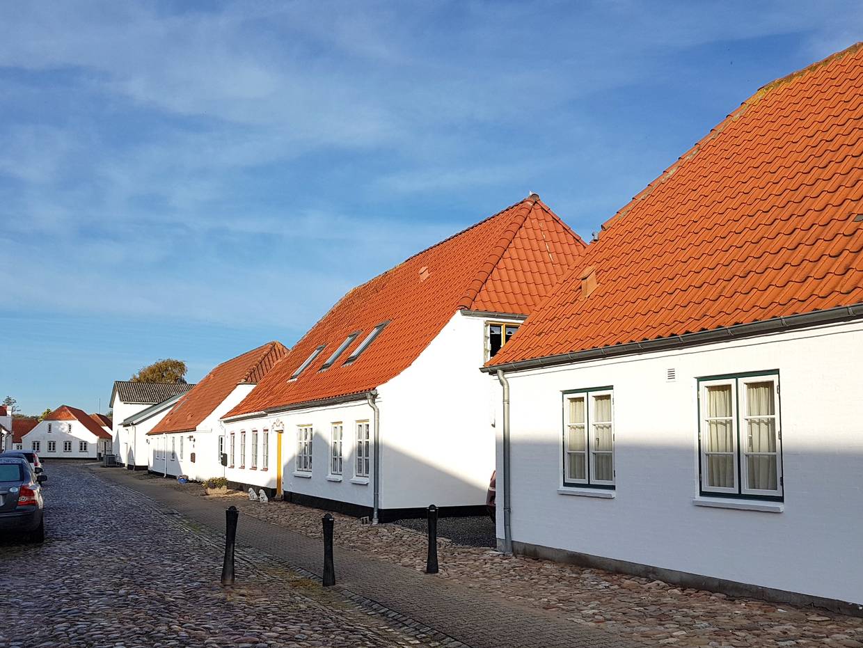 Weiße, recht schmucklose Häuser an einer Kopfsteinpflastergasse