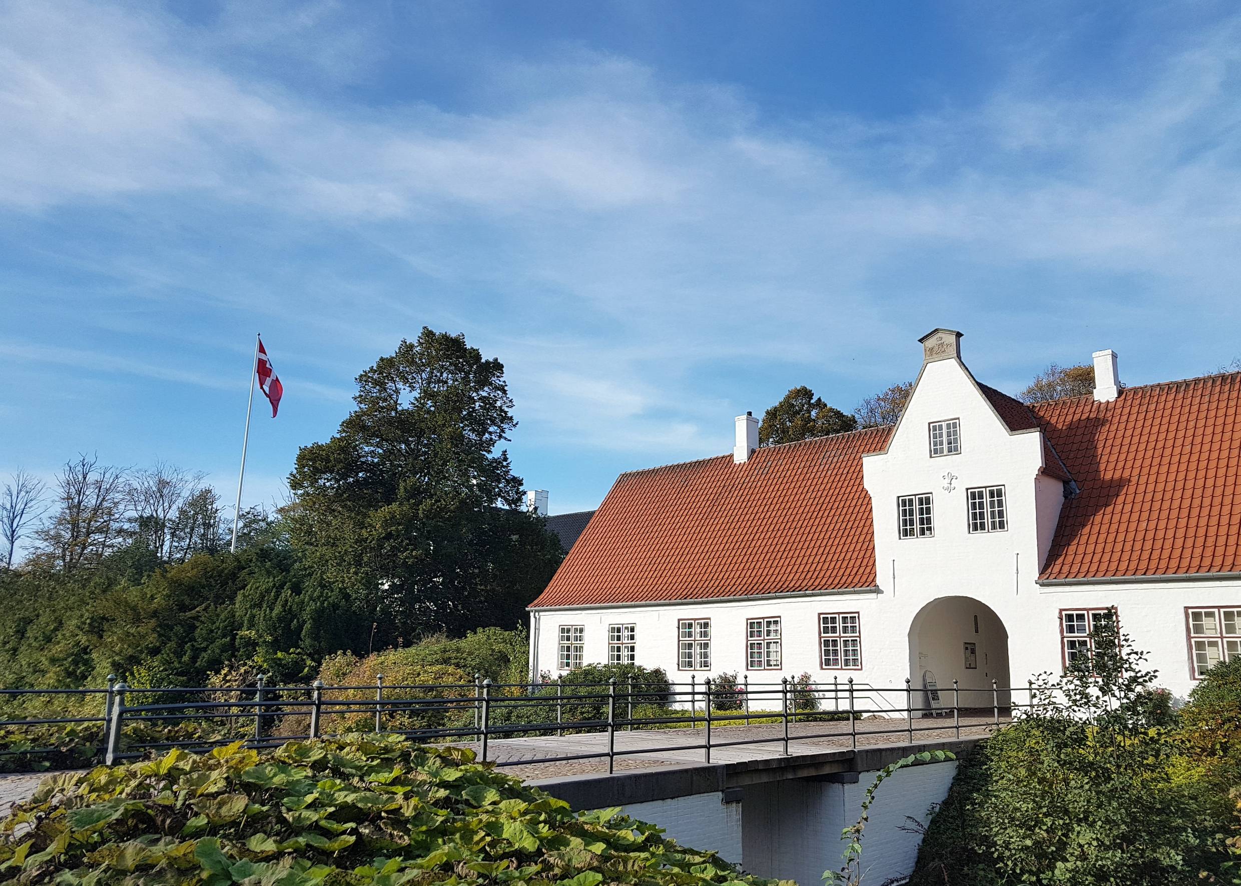 Weißes, kleines Schloss hinter einer Brücke über den Burggraben