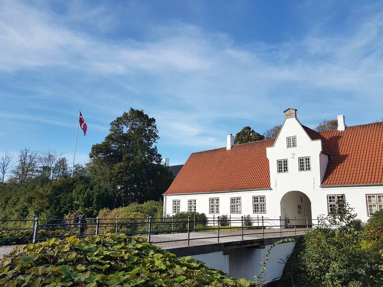 Weißes, kleines Schloss hinter einer Brücke über den Burggraben