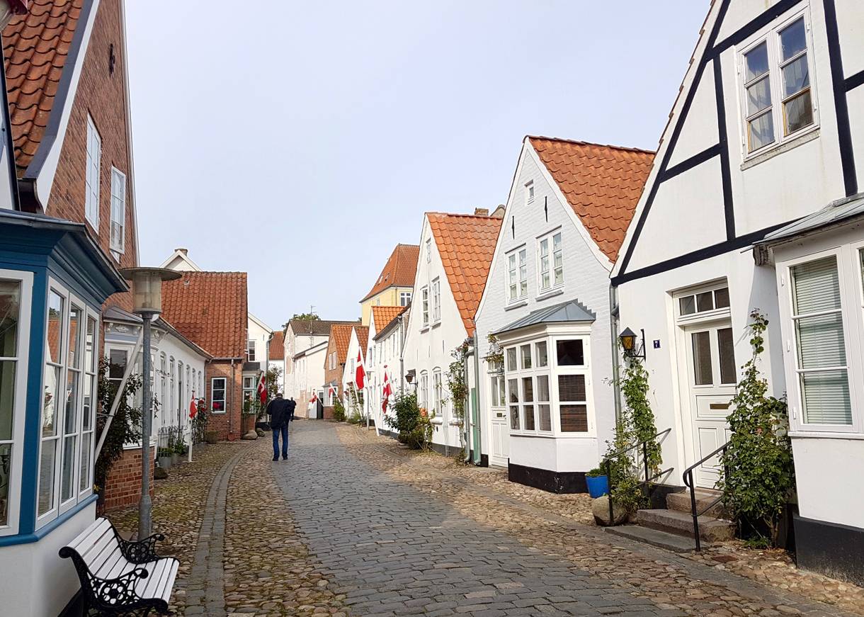 Kopfsteingasse in der Altstadt mit weißen Häusern und dänischen Flaggen