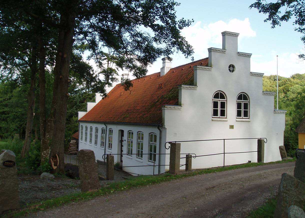 Weißes Haus mit Treppengiebel im Wald