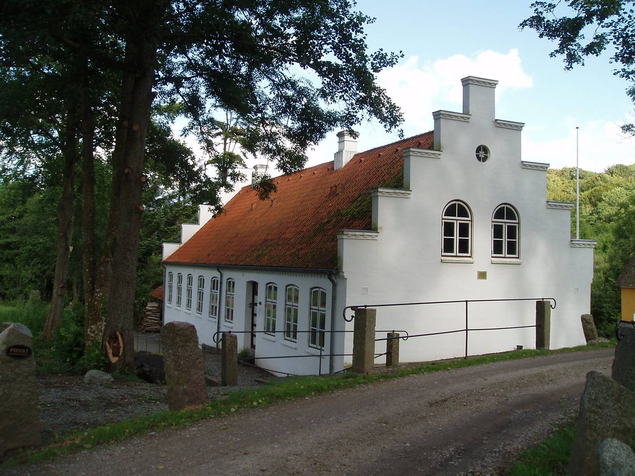 Weißes Haus mit Treppengiebel im Wald