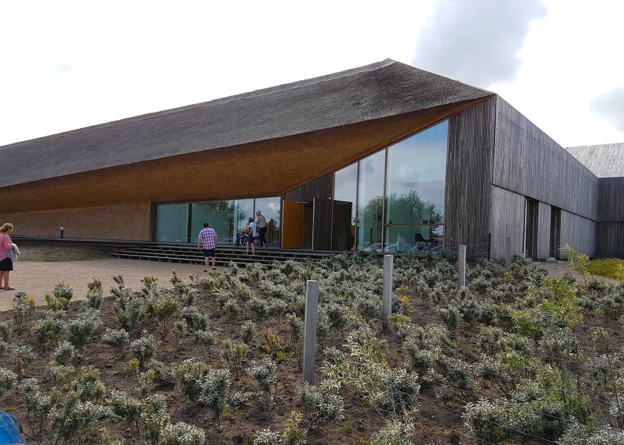 Modernes, graues Gebäude aus Holz mit Reet verkleidet