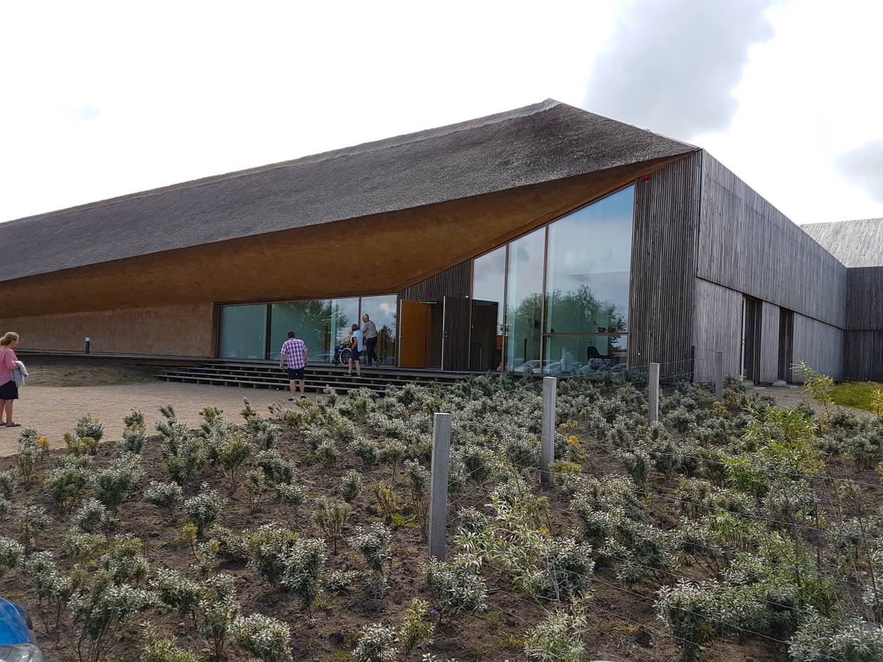 Modernes, graues Gebäude aus Holz mit Reet verkleidet