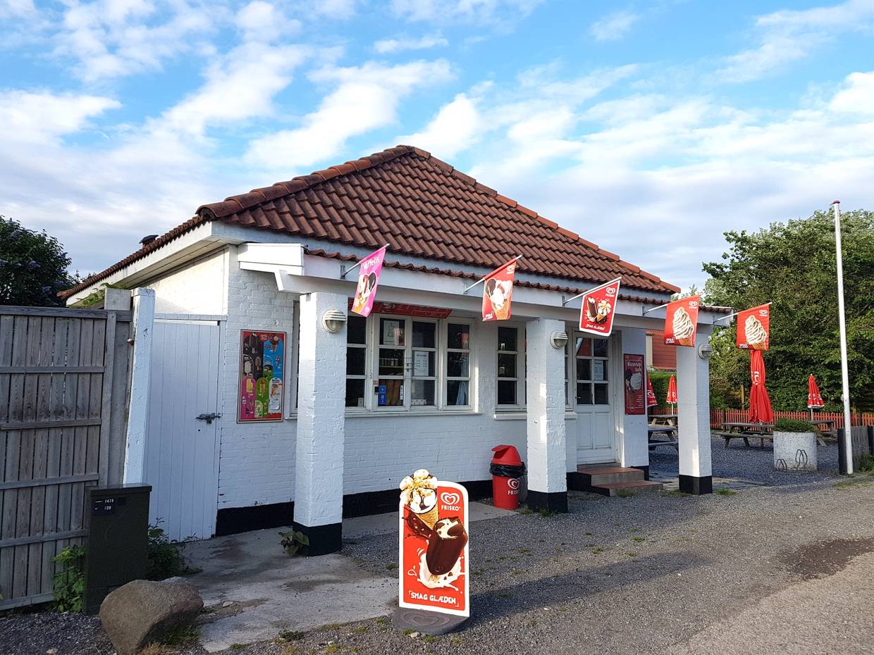 Imbissbude mit vielen Fähnchen am Haus und einer Terrasse im Hintergrund