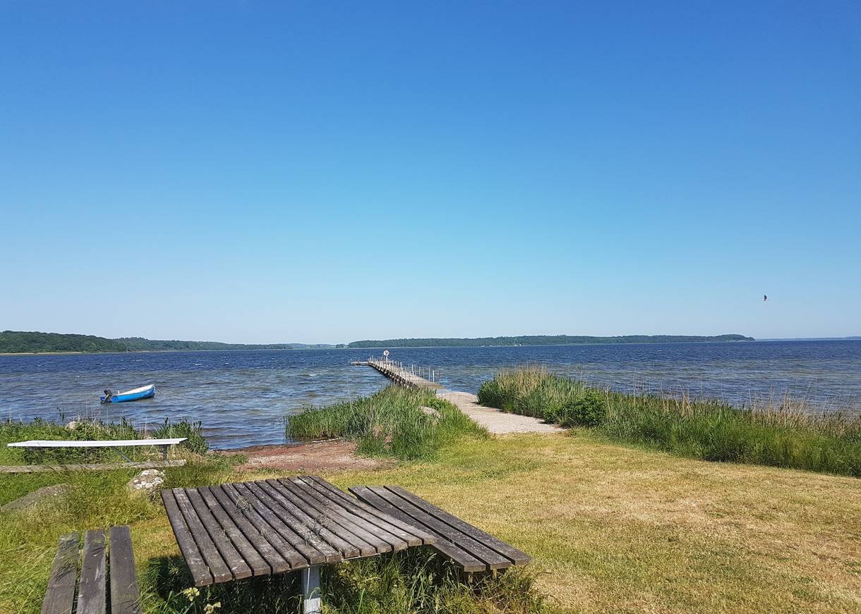Picknickbänke und ein Steg am Fjordufer