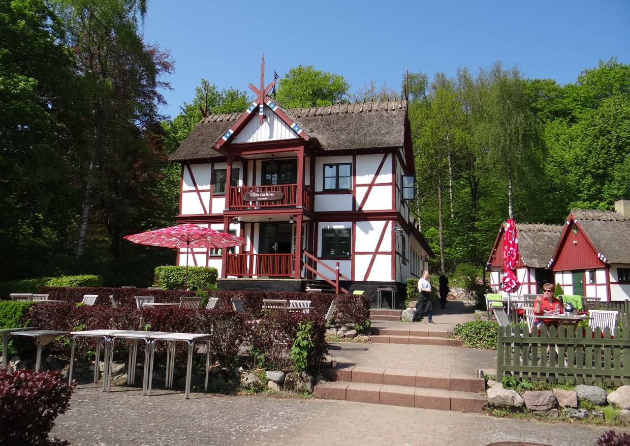 Altes Fachwerkhaus mit zwei Stockwerken und Reetdach, davor eine Außenterrasse