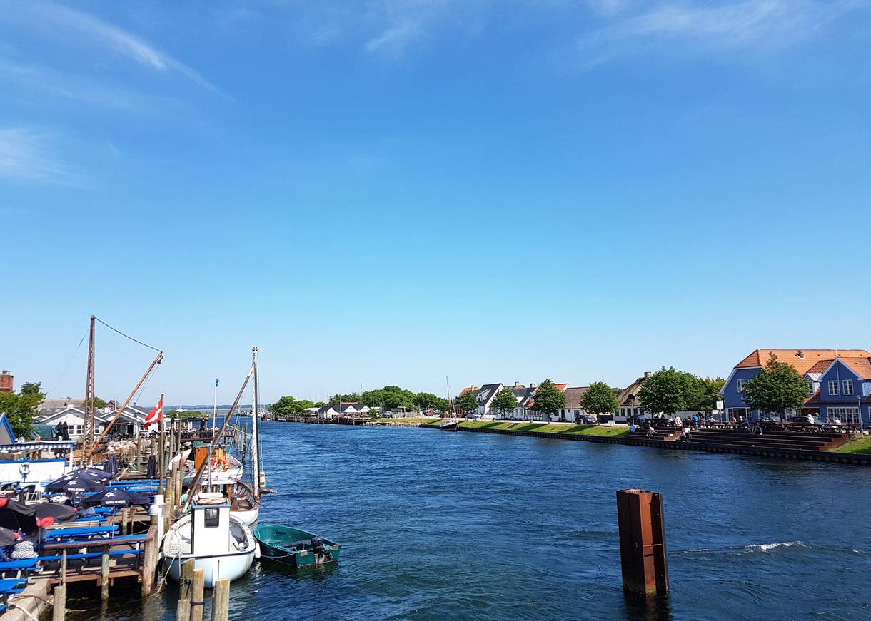 Blick auf einen Kanal mit weißen Fischerbooten und Restaurants