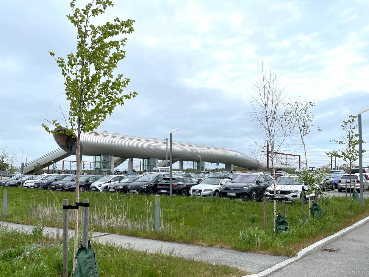 Blick über eine Parkplatz auf eine moderne Fußgängerbrücke am Bahnhof